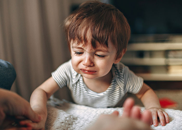 Crying toddler reaching out, highlighting how roommate’s guest treats her kid and a man’s concern as a parent. Crying toddler reaching out, highlighting how roommate’s guest treats her kid and a man’s concern as a parent.