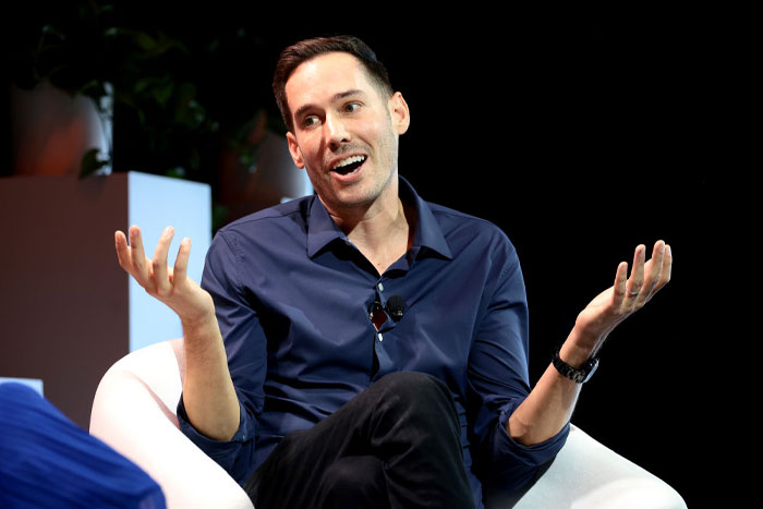 Carter Reum in a blue shirt gesturing with hands during a discussion about Carter Reum’s fortune and M13 Ventures growth.