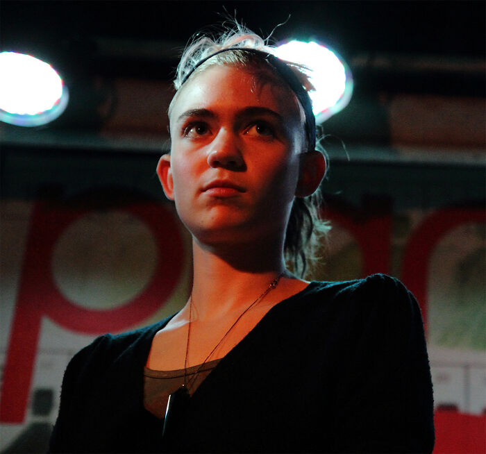 Young woman under dramatic lighting, conveying curiosity and intrigue about celebrity gossip and tea.