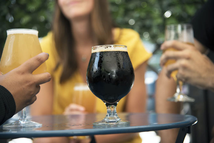People holding various beers at a table, illustrating national stereotypes about drinking culture and social habits.