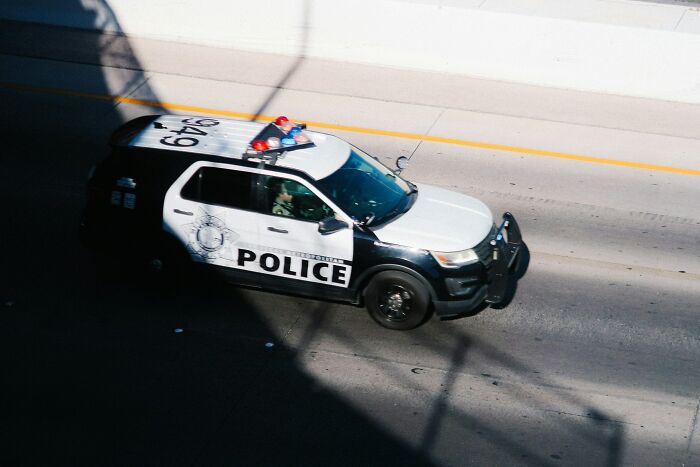 Police car driving on a highway, illustrating law enforcement related to Diddy's ex-assistant's testimony on threats.