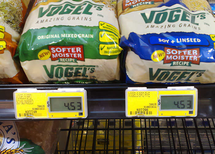 Packages of Vogel's bread with original mixed grain and soy linseed varieties on a grocery shelf with price tags, illustrating national stereotypes.