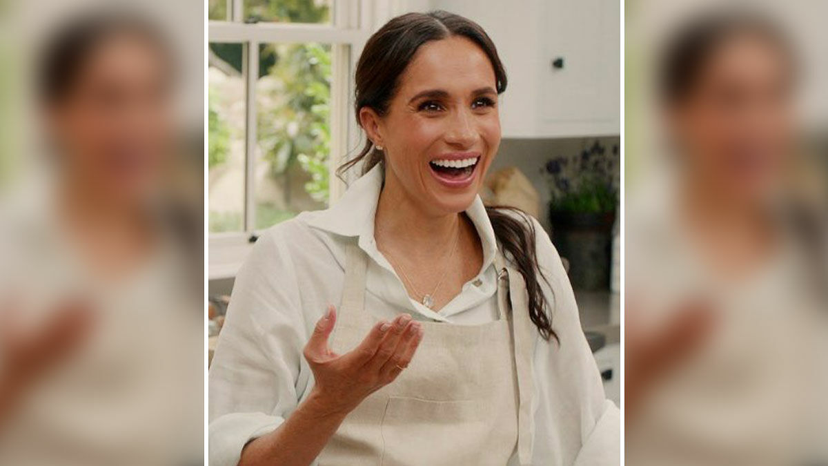 Meghan smiling and gesturing in a kitchen setting amid Harryu2019s crisis and mental health concerns involving King Charles.