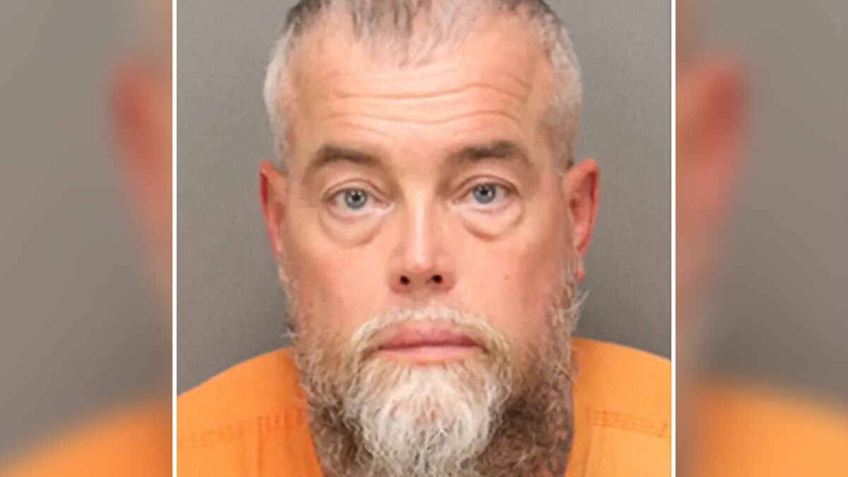 Man with gray beard in orange prison uniform, arrest photo relating to lottery win and arrest three days later.