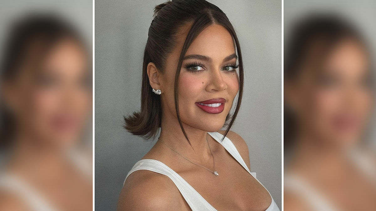 Khloe Kardashian smiling with styled hair and makeup, highlighting her recent plastic surgery transformation.