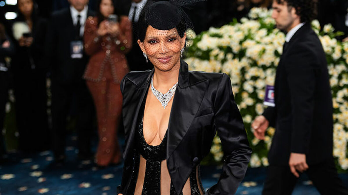 Halle Berry wearing a black satin blazer and sequined plunging dress with a black netted veil at a high-profile event.