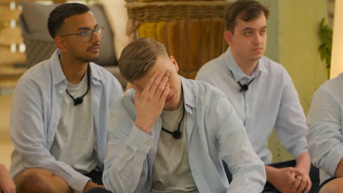 Three young men from the reality show Virgin Island sitting indoors during a raunchy challenge to lose their virginity.