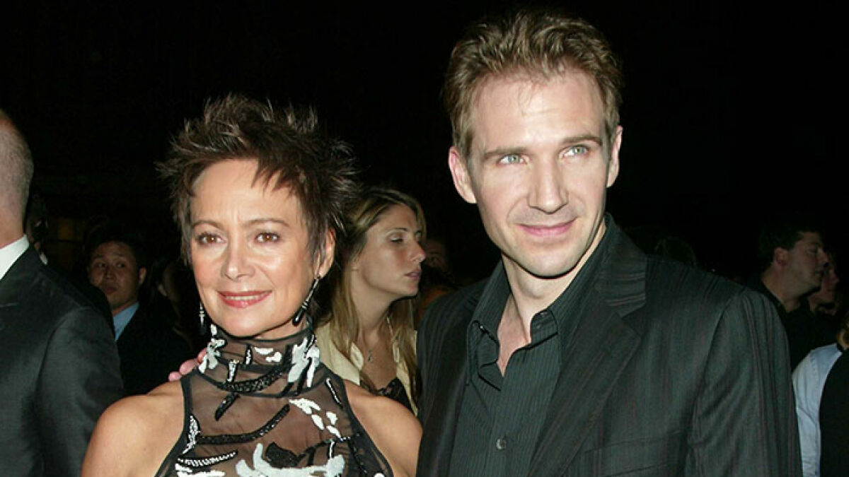 Ralph Fiennes and Francesca Annis posing together at a formal event with smiles in a nighttime setting.