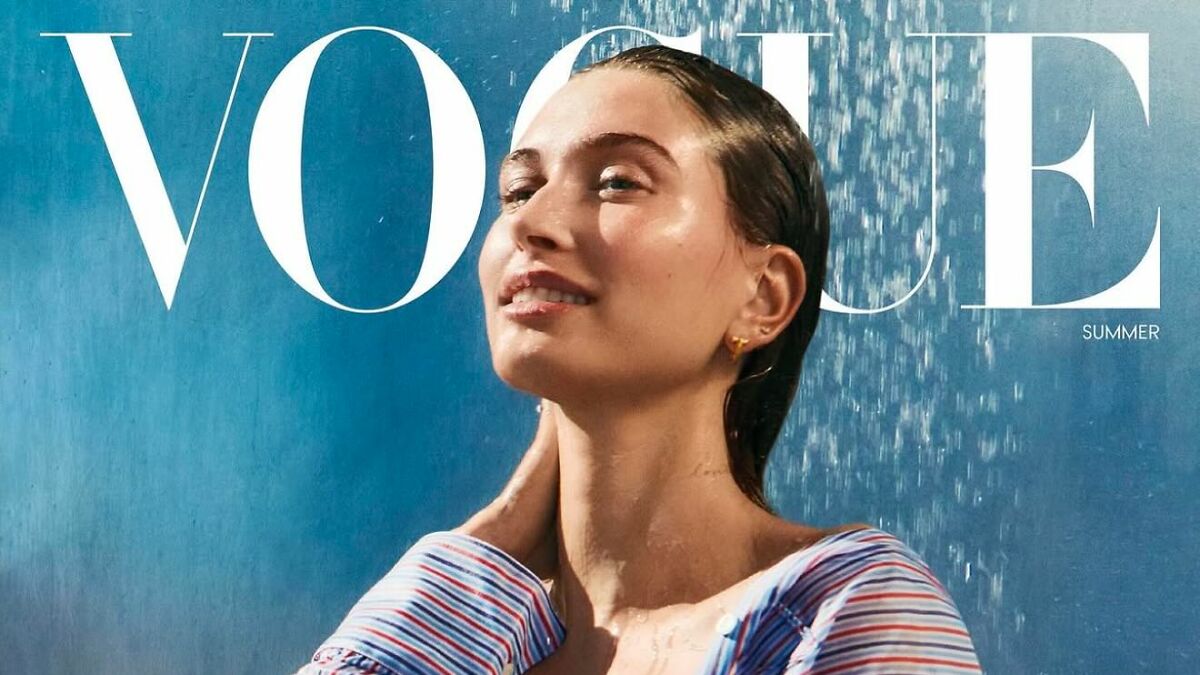 Hailey Bieber posing for Vogue cover photo with wet hair, wearing striped top, related to Kanye and Justin's Vogue remark.