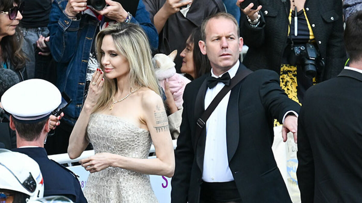 Angelina Jolie at event with bodyguard in a tense moment surrounded by fans and photographers.