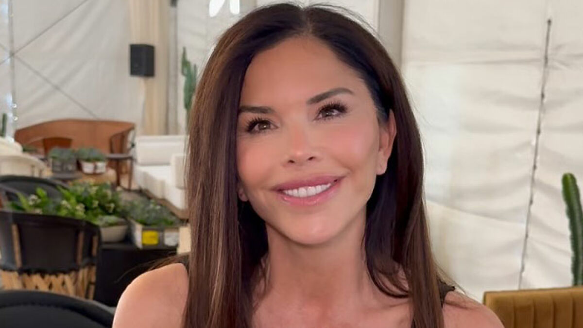 Lauren Su00e1nchez smiling with long dark hair in a casual indoor setting with plants and chairs in the background