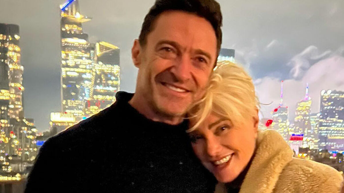 Hugh Jackman and Deborra-Lee Furness smiling together with a city skyline at night in the background.