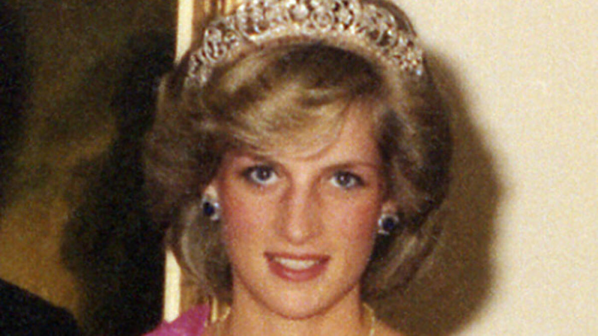 Princess Diana wearing a tiara and earrings, smiling in a formal portrait with soft lighting and a neutral background.