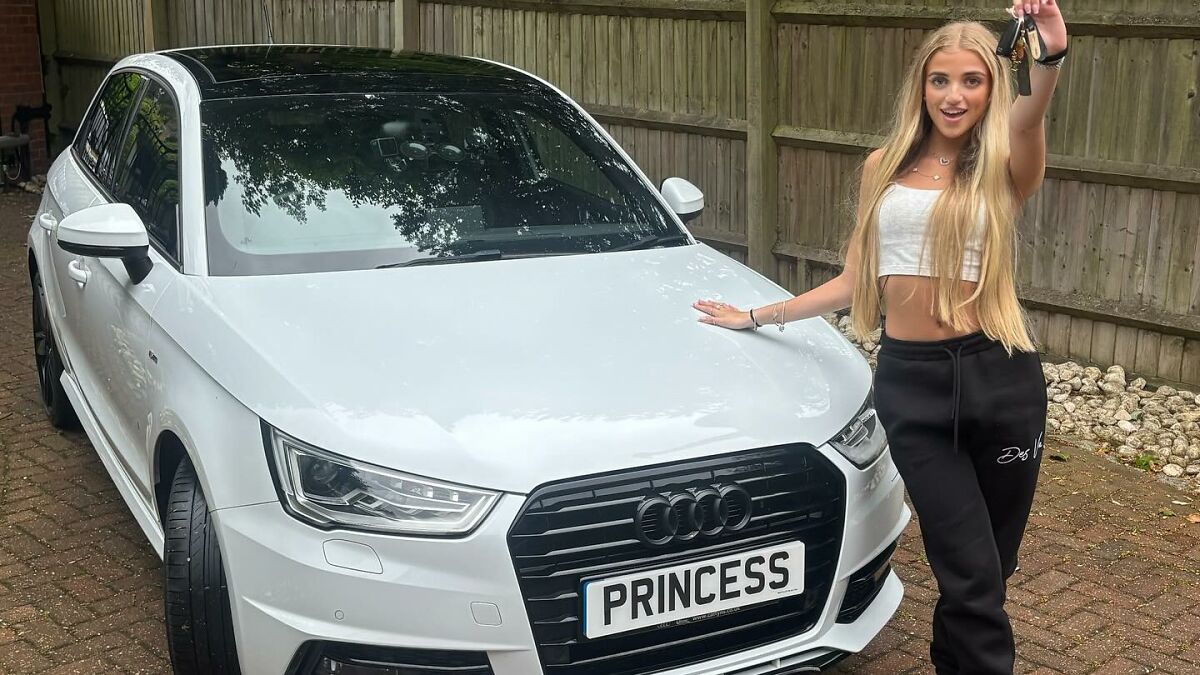 Princess Andre, 17, stands by her white Audi car in a driveway, holding up car keys and smiling confidently.