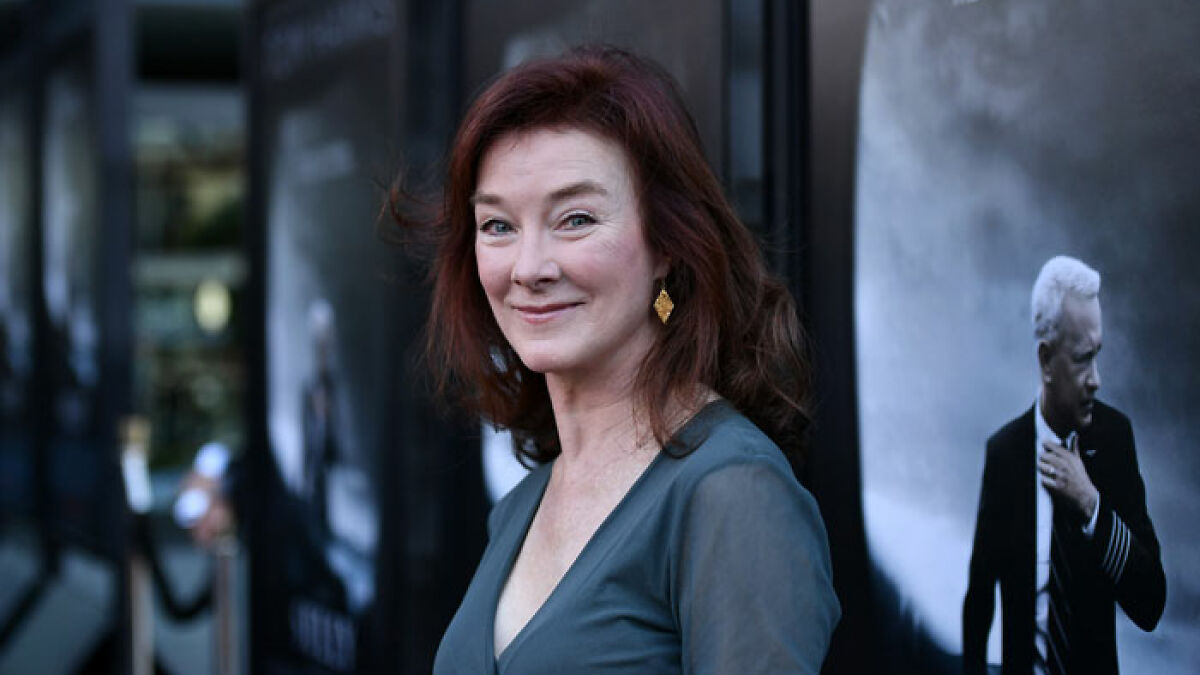 Actress known for Desperate Housewives and Young Sheldon smiling at an event with dark background and poster.