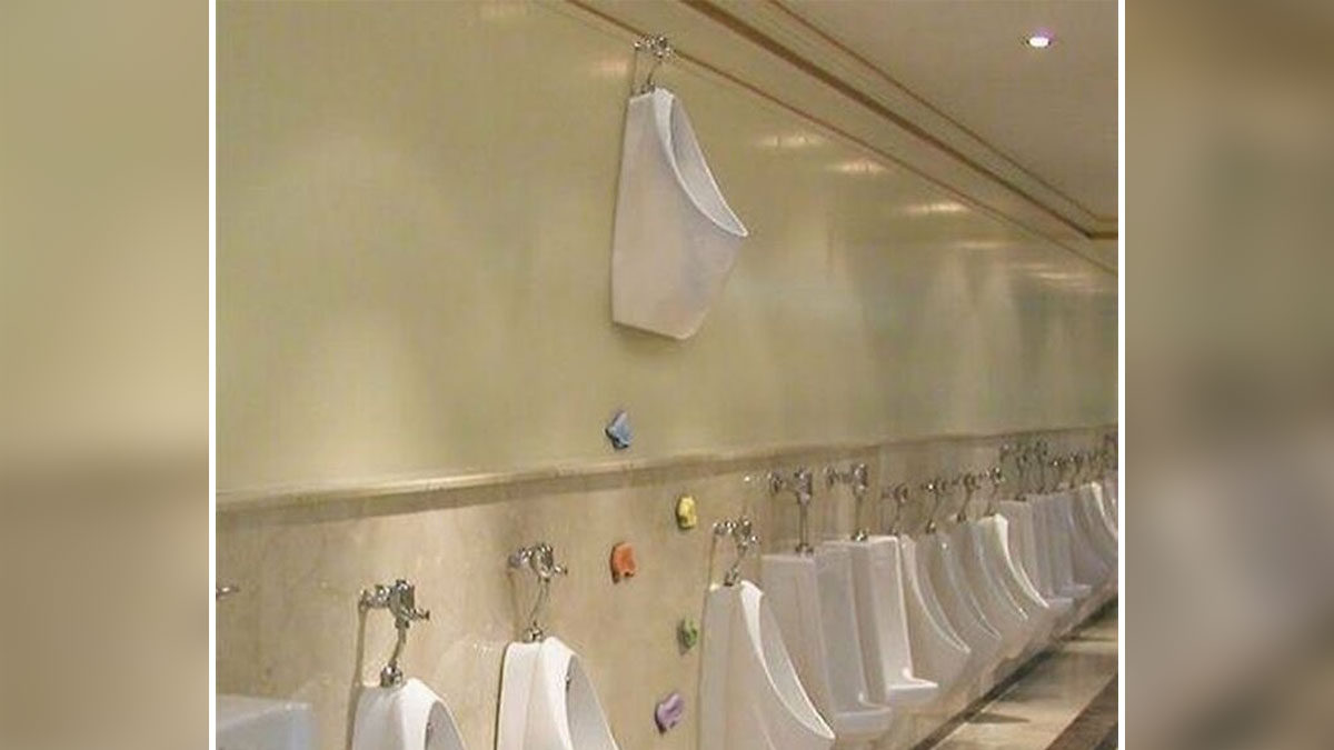 A row of urinals in a public restroom with a single urinal oddly mounted high on the wall, a cursed image.