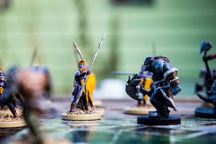 Miniature wargaming studio setup with detailed figurines engaged in a battle scene on a tabletop game board. Miniature wargaming studio setup with detailed figurines engaged in a battle scene on a tabletop game board.