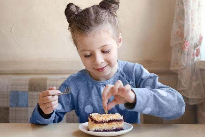 Young girl in blue shirt eating cake, highlighting confusion over eggs as dairy in dairy-free desserts debate. Young girl in blue shirt eating cake, highlighting confusion over eggs as dairy in dairy-free desserts debate.