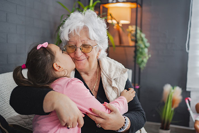 Grandmother and granddaughter hugging affectionately indoors, highlighting mom booked vacation and won’t babysit kids. Grandmother and granddaughter hugging affectionately indoors, highlighting mom booked vacation and won’t babysit kids.