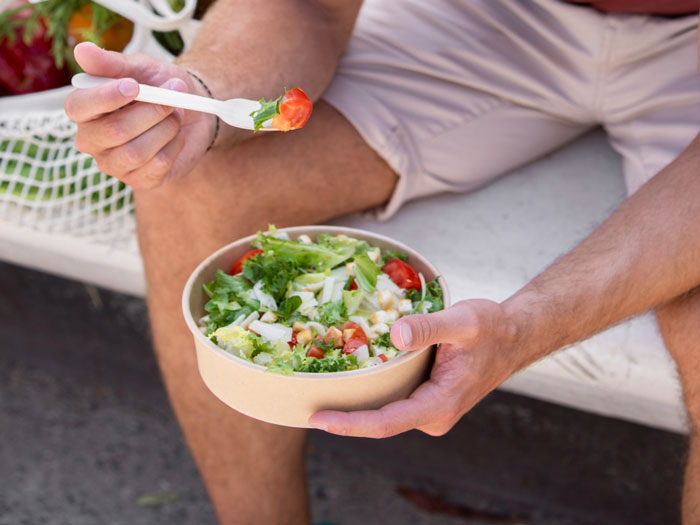 Person sitting outdoors holding a bowl of salad with fish and cheese, reflecting David Attenborough's dietary choice. Person sitting outdoors holding a bowl of salad with fish and cheese, reflecting David Attenborough's dietary choice.