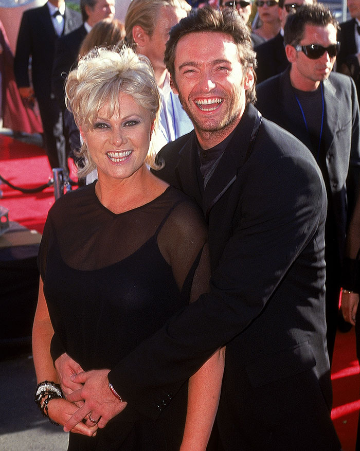 Deborra-Lee Furness and Hugh Jackman smiling together on the red carpet during a public event. Deborra-Lee Furness and Hugh Jackman smiling together on the red carpet during a public event.