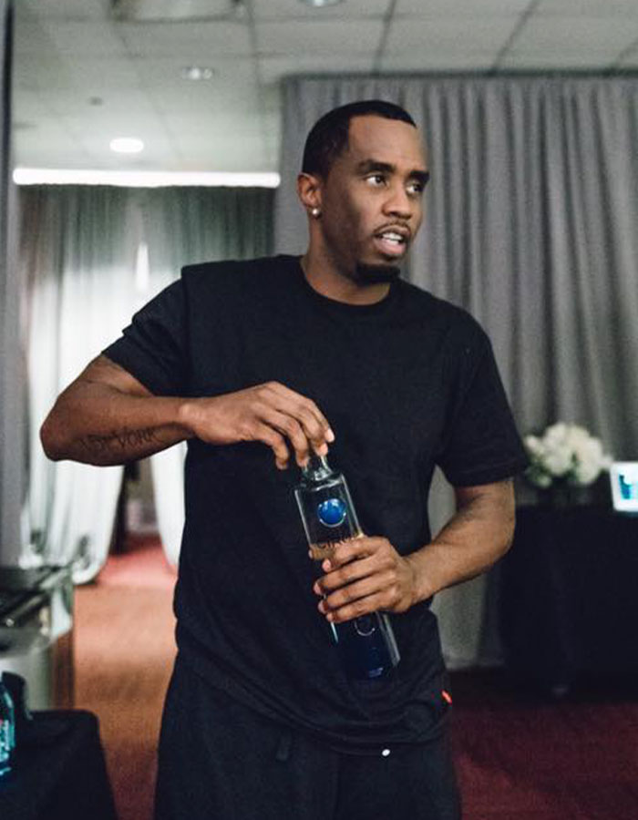 Diddy in a black shirt holding a bottle indoors, highlighting reports of his revolting eating habits revealed by former staff. Diddy in a black shirt holding a bottle indoors, highlighting reports of his revolting eating habits revealed by former staff.
