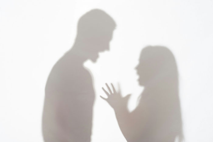 Silhouettes of a man and woman arguing passionately, illustrating domestic violence debate between genders. Silhouettes of a man and woman arguing passionately, illustrating domestic violence debate between genders.
