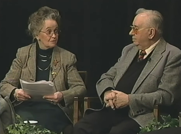 Two elderly people discussing the haunted Annabelle doll's chilling history in a small indoor interview setting. Two elderly people discussing the haunted Annabelle doll's chilling history in a small indoor interview setting.