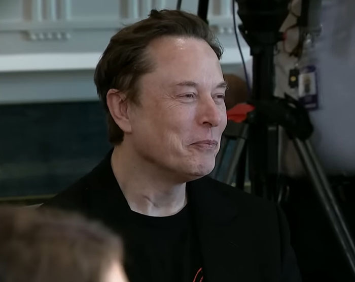 Elon Musk in a black jacket smiling during an indoor event, related to Tesla CEO search updates and leadership changes. Elon Musk in a black jacket smiling during an indoor event, related to Tesla CEO search updates and leadership changes.