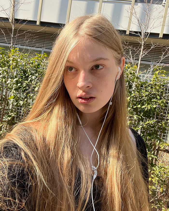Elon Musk's trans daughter Vivian wearing earbuds outdoors with long blonde hair in a natural light setting. Elon Musk's trans daughter Vivian wearing earbuds outdoors with long blonde hair in a natural light setting.