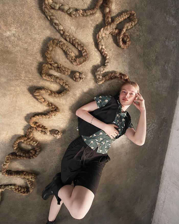 Vivian Musk modeling debut lying on floor with long braided hair arranged around, showcasing unique fashion style. Vivian Musk modeling debut lying on floor with long braided hair arranged around, showcasing unique fashion style.