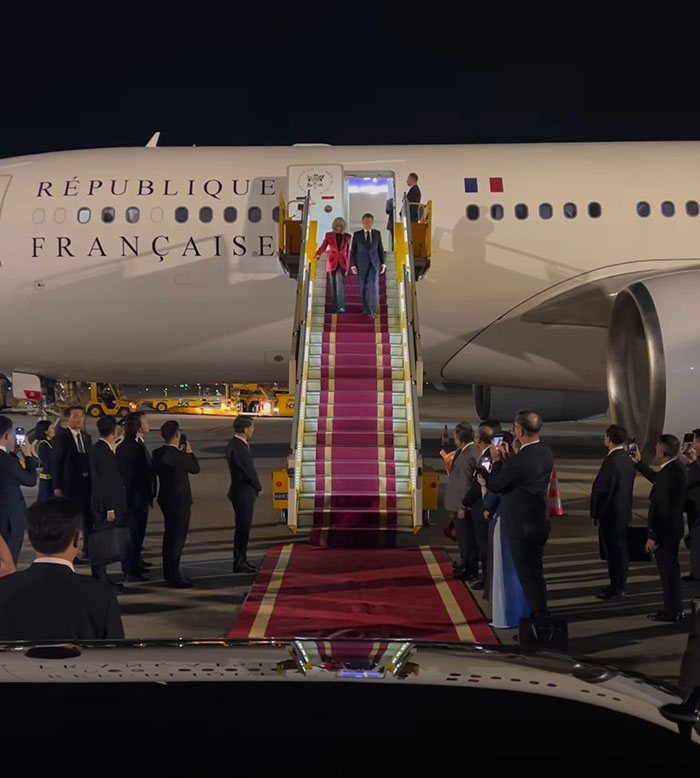 French President Emmanuel Macron and wife arriving on airplane stairs during official event with crowds watching at night. French President Emmanuel Macron and wife arriving on airplane stairs during official event with crowds watching at night.