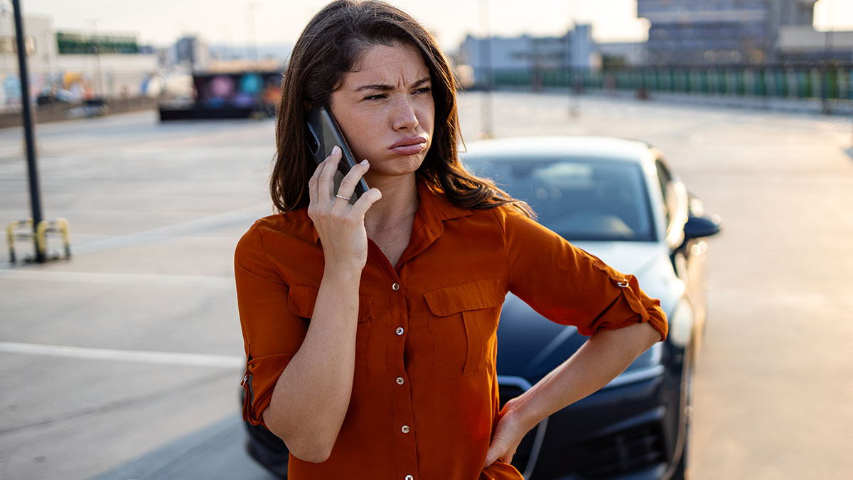 Woman frustrated on phone in parking lot after trying to save parking spot for hubby, embodying Karen behavior stereotype.