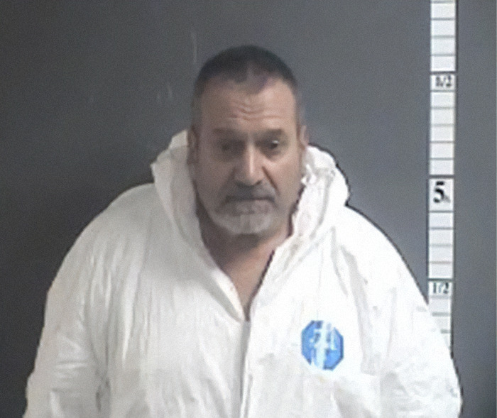 Mugshot of a man wearing a white forensic suit standing against a height measurement background. Mugshot of a man wearing a white forensic suit standing against a height measurement background.