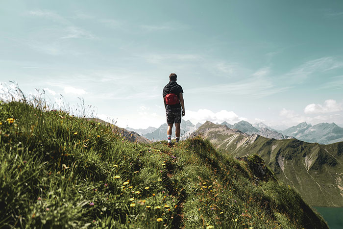 Person with a red backpack hiking on a grassy mountain trail, reflecting on memories of an ex-fiance Valentine Day. Person with a red backpack hiking on a grassy mountain trail, reflecting on memories of an ex-fiance Valentine Day.