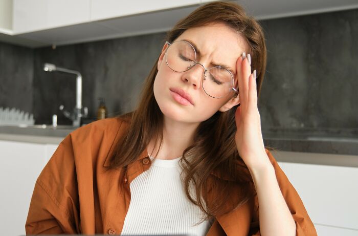Young woman with glasses looking stressed, representing jealous grandparents upset about ex-in-laws giving money to kid. Young woman with glasses looking stressed, representing jealous grandparents upset about ex-in-laws giving money to kid.