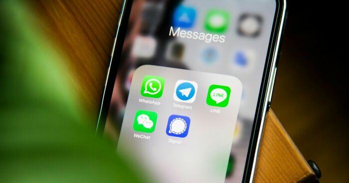 Smartphone screen showing messaging apps WhatsApp, Telegram, LINE, WeChat, and Signal for unhinged text sharing.