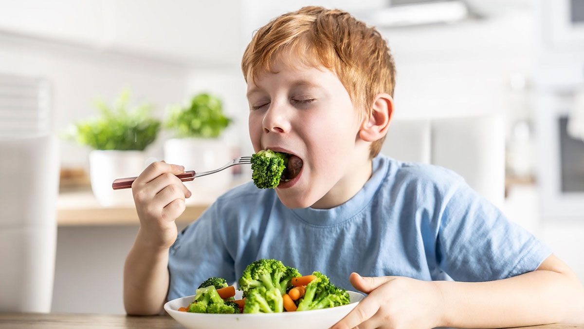 Young boy eating broccoli with a fork showing veggie love and choosing healthy rabbit food over chicken at home meal