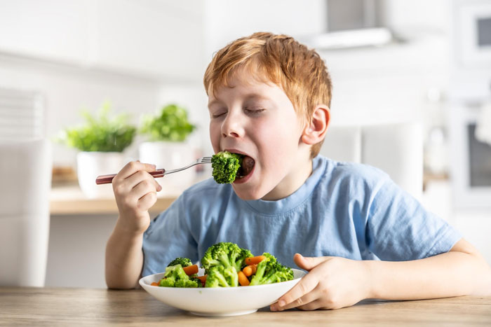 Young boy enjoying a healthy serving of broccoli and vegetables, showing strong veggie love over other meals. Young boy enjoying a healthy serving of broccoli and vegetables, showing strong veggie love over other meals.