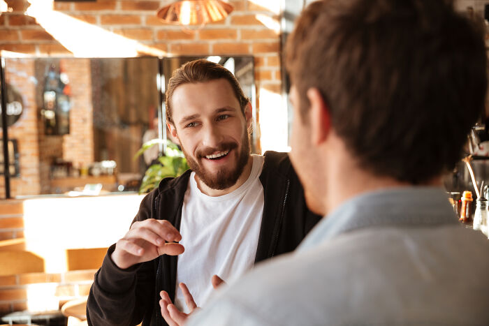 Two men having a heartfelt conversation about ultimatums and lost friendships in a cozy, sunlit cafe setting.