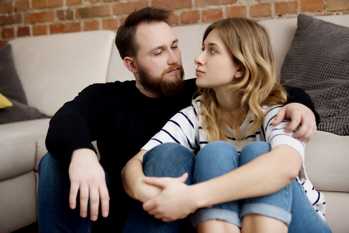 Young couple sitting closely on floor, showing emotional intimacy and reflecting on turning back on female friends after demand.