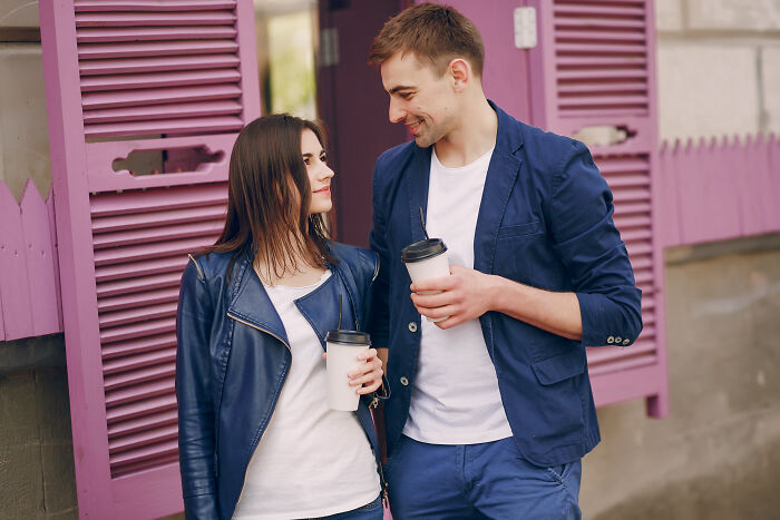 Young couple drinking coffee and smiling, illustrating men who turned their back on female friends for their girlfriend.
