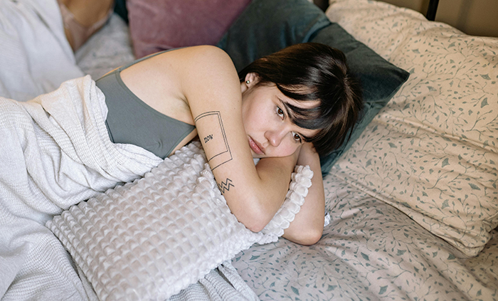 Young woman lying on bed looking upset, illustrating toxic roomie conflict and eviction attempt in shared home. Young woman lying on bed looking upset, illustrating toxic roomie conflict and eviction attempt in shared home.