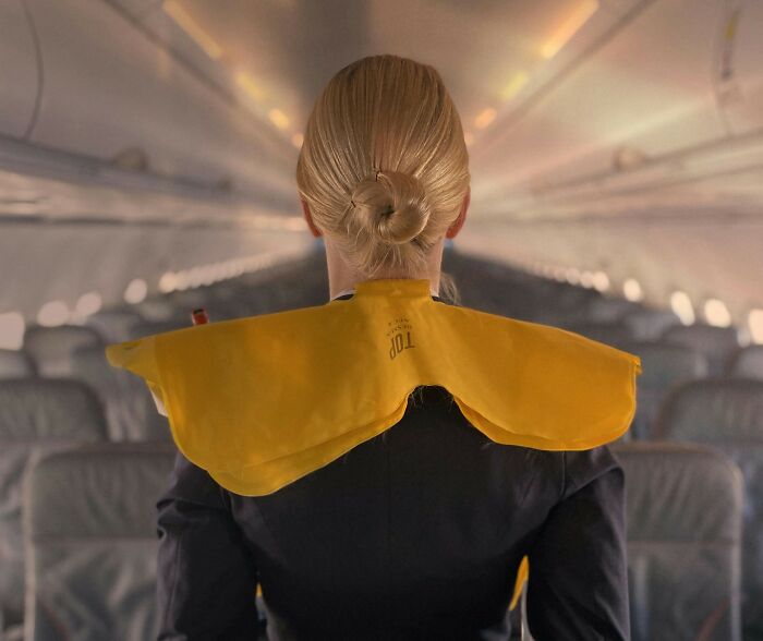 Flight attendant demonstrating safety procedures inside an airplane cabin, highlighting common passenger habits annoyance.