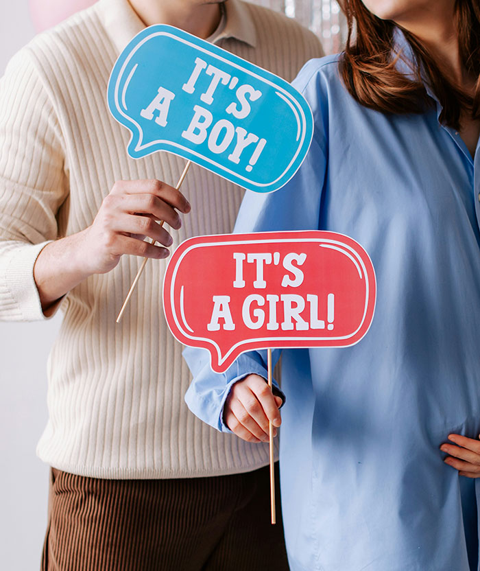 Couple holding gender reveal signs saying its a boy and its a girl during baby's gender reveal celebration event. Couple holding gender reveal signs saying its a boy and its a girl during baby's gender reveal celebration event.