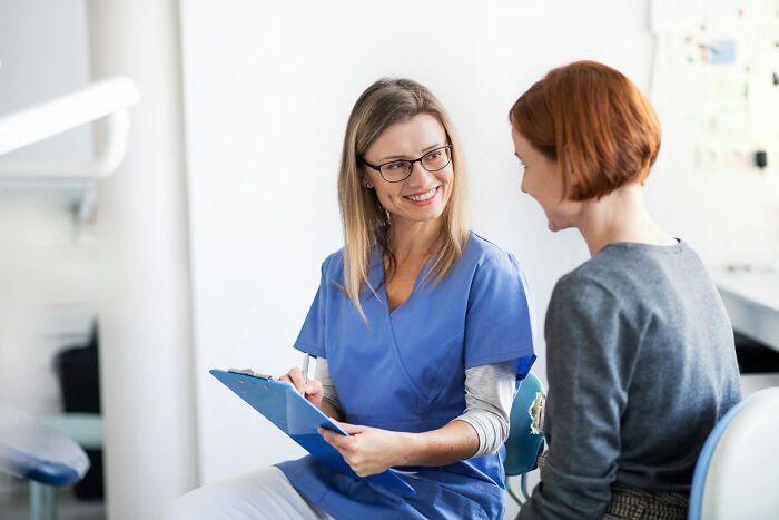 Healthcare professional smiling and discussing industry secrets with a patient in a bright clinical setting.