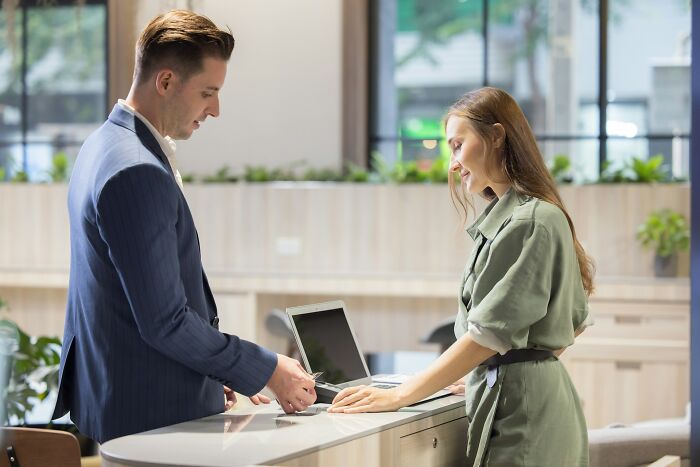Two professionals sharing industry secrets while reviewing information on a laptop behind closed doors in an office setting