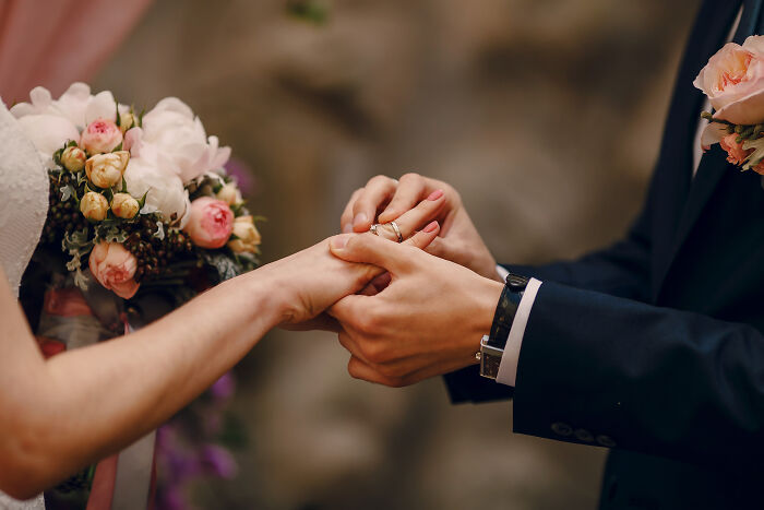 Man holding and placing ring on partner’s hand next to bouquet, illustrating men who lost amazing partners and their life now.