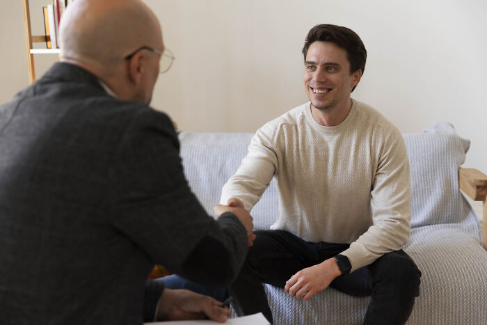 Two men shaking hands in a counseling session, illustrating support for men who lost amazing partners sharing life experiences.