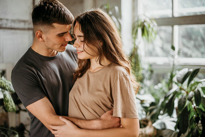 Young couple embracing tenderly indoors, representing men who lost amazing partners and share their life experiences now.